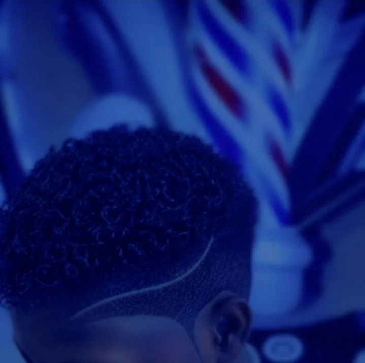 Close-up of a precision fade haircut by SPA_Fades against a barber pole